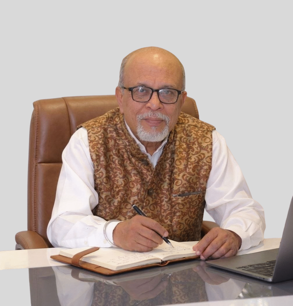 Indian business professional seated at a desk with laptop and notebook
